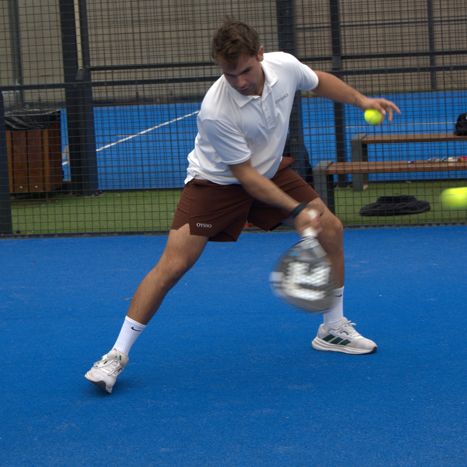 Padel player crouching to hit off the back wall