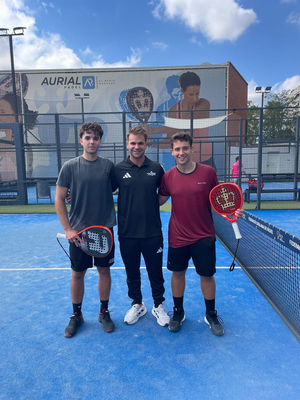 Max, head coach, with two players smiling on a blue padel court